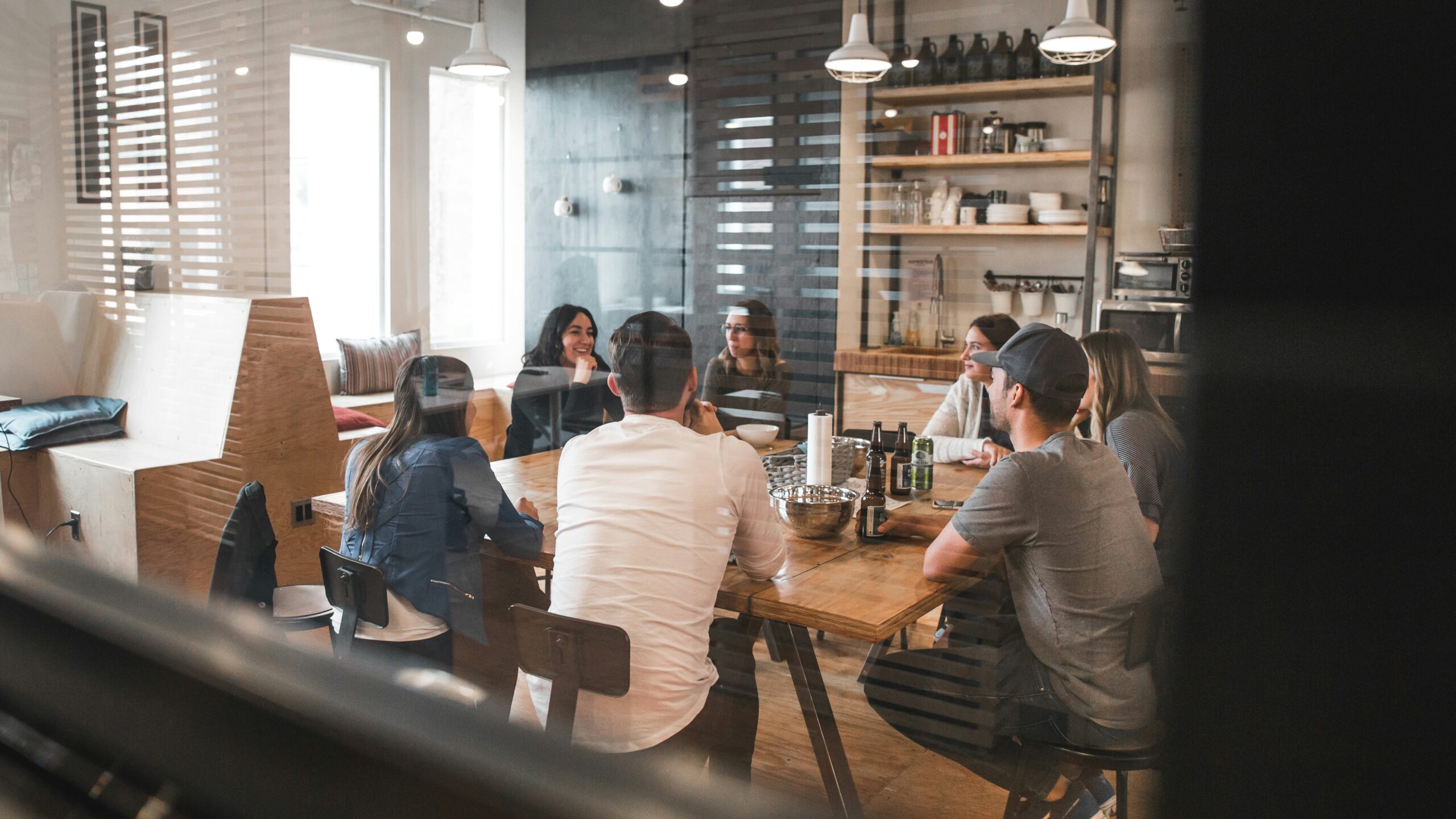 A group of people sits around a table in a casual meeting room. To make the most of college visits, set up some meetings with groups that interest you.